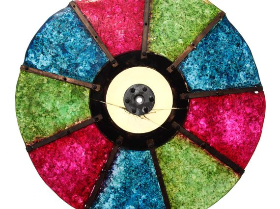 A colour photograph of a circular disc made up of red, blue and green semi-opaque panes against a white background. There are 2 of each colour alternating and connected by a central solid hub.